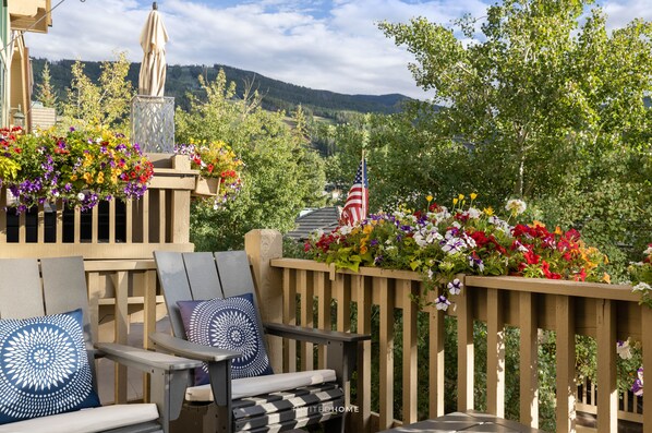 A balcony with outdoor seating, a statue, and a view of mountains.