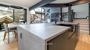 A modern kitchen with a large island, built-in appliances, and a view of a snowy landscape. - Urban Home at The Aspens by InvitedHome | Hike In/Out, Near BC Village, Decks (Avon)