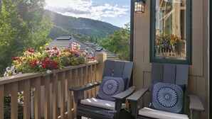 A balcony with two Adirondack chairs, a wooden railing, and a flower box with various flowers. - Urban Home at The Aspens by InvitedHome | Hike In/Out, Near BC Village, Decks (Avon)