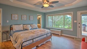 A bedroom with a bed, ceiling fan, large windows, and artwork on the wall. - Roomy Texas Lake Retreat w/ Private Boat Ramp (Frankston)
