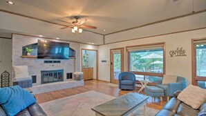 A spacious living room with a stone fireplace, comfortable seating, and large windows offering views of the outdoors. - Roomy Texas Lake Retreat w/ Private Boat Ramp (Frankston)