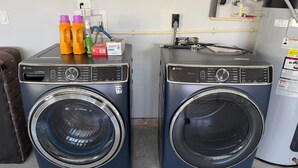 Two front-loading washing machines with control panels, a power outlet, and a water heater on the wall.
