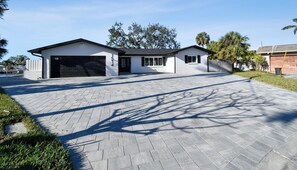 Una casa moderna de dos pisos con garaje, entrada pavimentada y césped bien cuidado.
