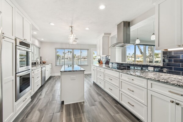 A modern kitchen with white cabinetry, granite countertops, and a central island.