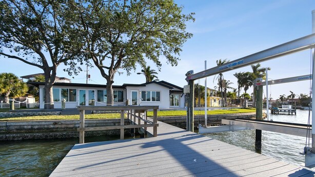 A waterfront property with a dock, a white building, and a tree.