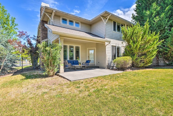 A two-story house with a covered patio, a front door, and a small garden area.