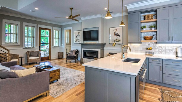 A spacious kitchen with grey cabinets, a central island, and a fireplace. - Sunny FL Home 'Miss Millie’s Landing’' w/ Deck! (Santa Rosa Beach)