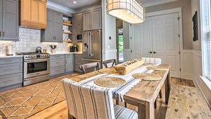 A modern kitchen with grey cabinets, stainless steel appliances, and a wooden dining table with woven placemats. - Sunny FL Home 'Miss Millie’s Landing’' w/ Deck! (Santa Rosa Beach)
