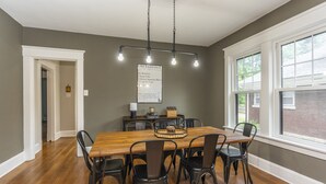 A dining area with a wooden table, black chairs, and a hanging light fixture. - Stylish 2Bed/2Ba home in Chevy Chase, close to Downtown and UK! (Lexington)