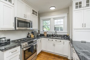 A modern kitchen with white cabinets, a stainless steel stove, and a black countertop.