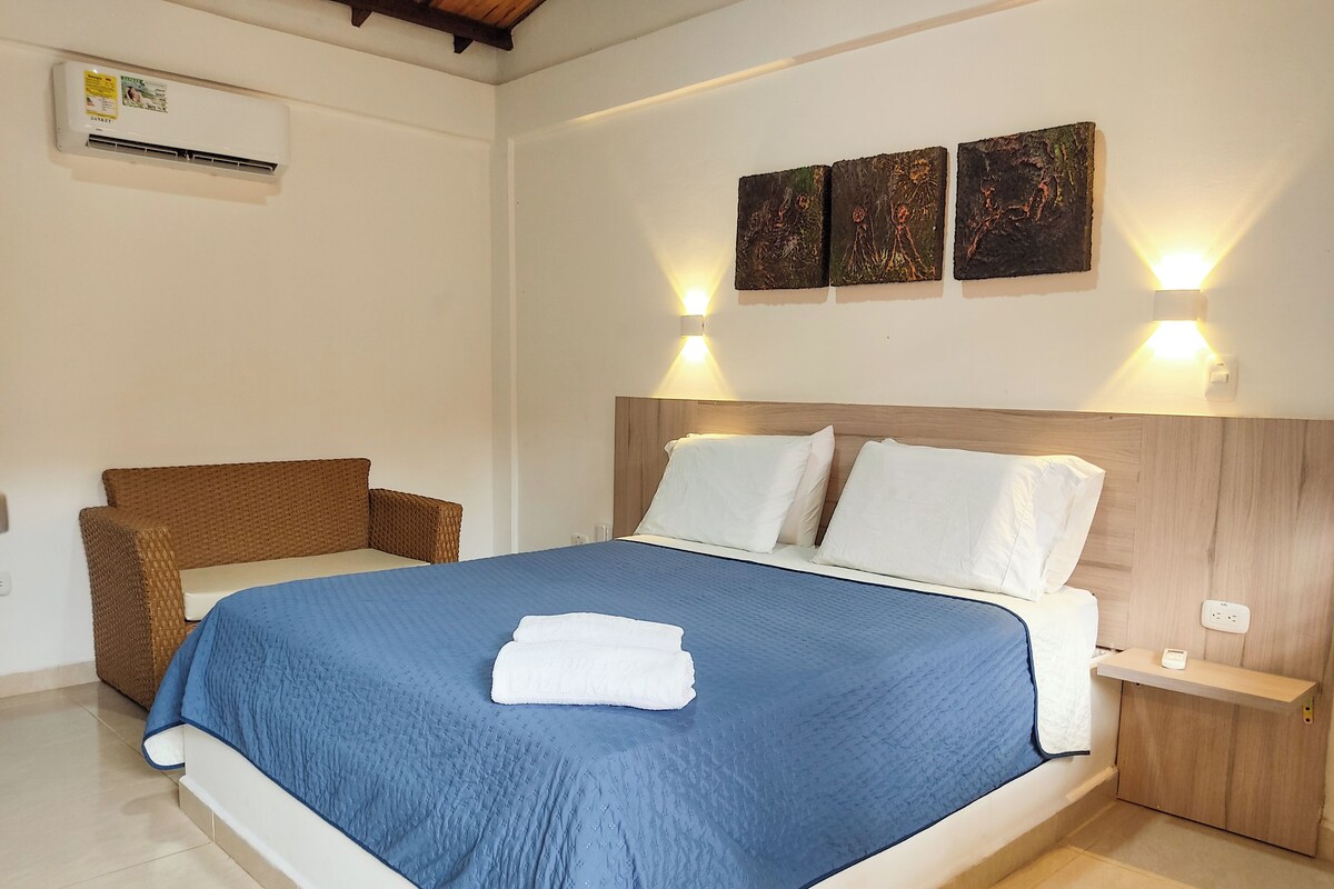 A bedroom with a large bed, a wooden headboard, and a wall-mounted air conditioner.