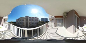 A balcony with a view of high-rise buildings, a white railing, and a table with chairs.