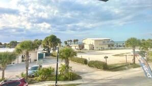 A parking lot with a building in the background, palm trees, and a clear sky.