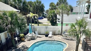 A swimming pool with lounge chairs and a brick patio.