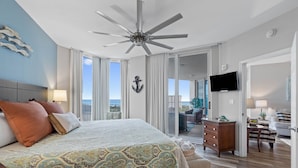 Une chambre d’hôtel avec un grand lit, un ventilateur de plafond, une télévision et un balcon avec vue.