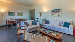 A modern living room with a sofa, coffee table, and dining area with chairs. - SUPER ATTICO - Sea view and large terrace (Rapallo)