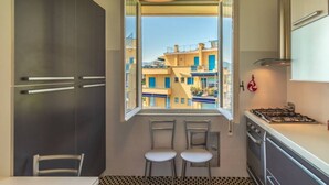 A kitchen with a window, two chairs, a table, and a stove. - SUPER ATTICO - Sea view and large terrace (Rapallo)