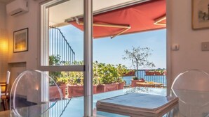 A room with a glass door leading to an outdoor area, a red umbrella, and a view of a staircase and greenery. - SUPER ATTICO - Sea view and large terrace (Rapallo)