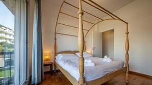 A four-poster bed in a room with a large window, a nightstand, and a door. - SUPER ATTICO - Sea view and large terrace (Rapallo)