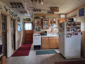 Een keuken met houten kastjes, een fornuis, een koelkast en diverse visserijsouvenirs.