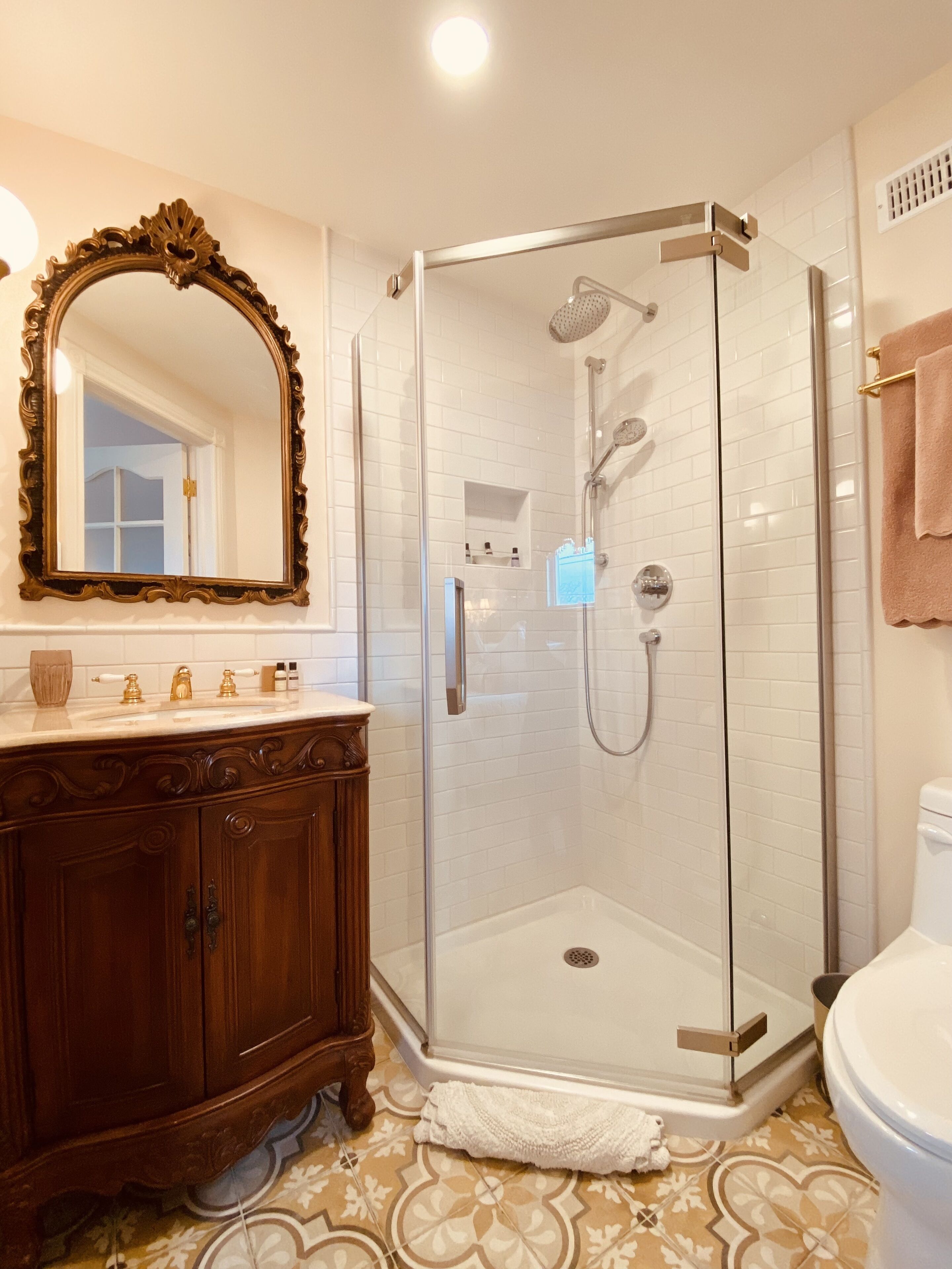 A bathroom with a glass-enclosed shower, a wooden vanity, and a large mirror.