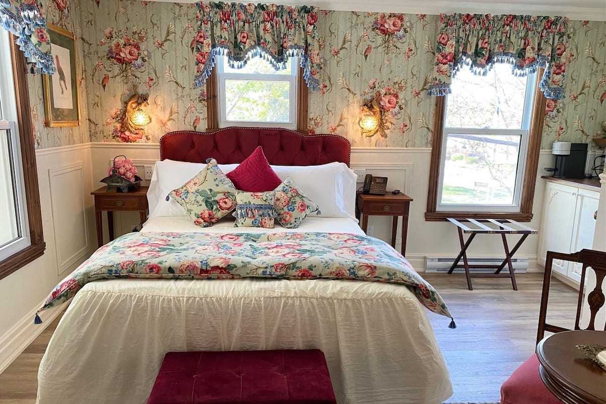 A bedroom with a large bed, floral wallpaper, and two bedside lamps.