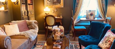 A cozy living room with a brown sofa, a blue armchair, a wooden coffee table, and a bookshelf filled with books.