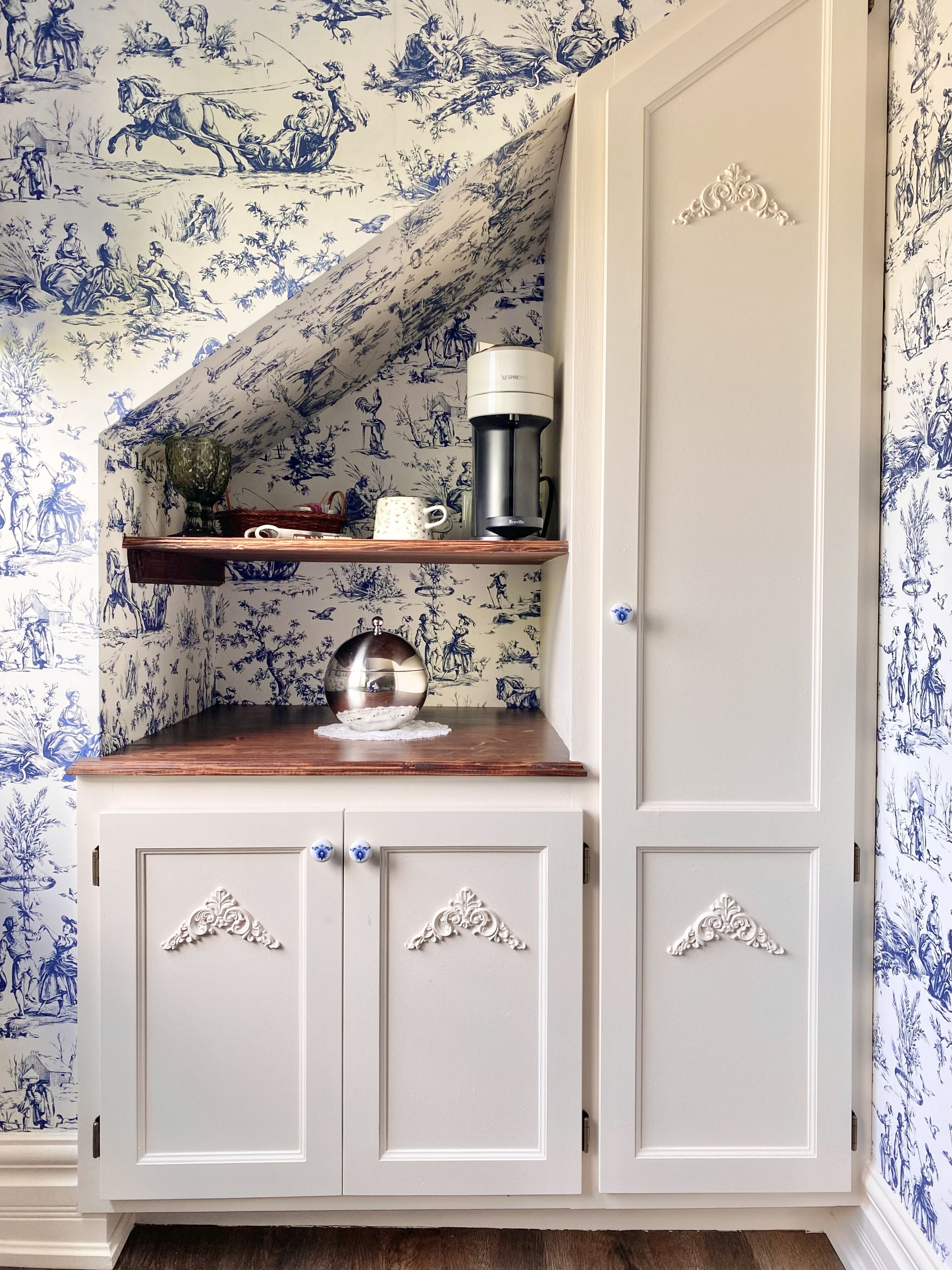 A kitchen with a coffee maker, a decorative bowl, and a shelf with a mug.