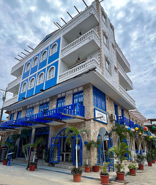 A multi-story building with blue-framed windows and doors, a stone facade, and a sign reading "KAPADOKI HOTEL." - ROCIO BOUTIQUE HOTEL (Manglaralto)
