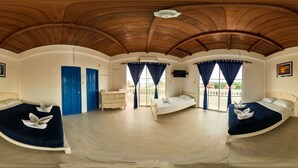 A spacious room with curved ceilings, two beds, a dresser, and a balcony with blue curtains.