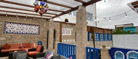 Un patio al aire libre con mobiliario de mimbre, un muro de piedra y una barandilla azul.