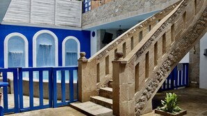 A stone staircase with a blue railing leading to a balcony.