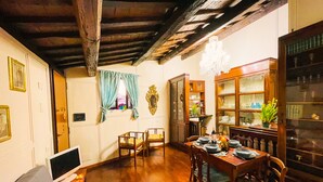 Un comedor con mobiliario de madera, una araña y un aparador con puertas de vidrio.