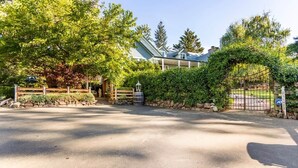 A gated driveway leading to a house with a stone wall and a metal gate.