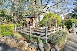 A garden with a wooden deck, a gazebo, and a stone wall.