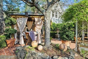 Uma área de estar ao ar livre coberta, com mesa, cadeiras e toldo.