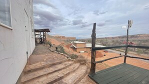 Escadaria que leva a uma área coberta, com vista para uma paisagem desértica e edifícios ao longe.