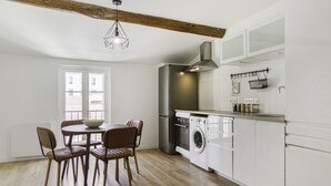 A modern kitchen with a dining area, featuring a washing machine, a refrigerator, and a hanging rack. - Appartement Ventoux - Welkeys (Avignon)