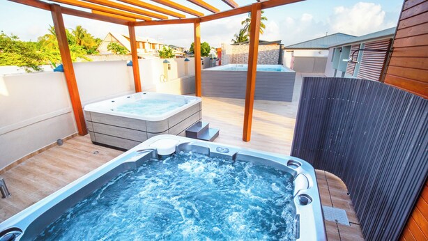 Un jacuzzi bajo una pérgola de madera con vista a una zona residencial.