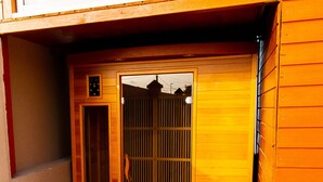 A small wooden room with a sliding door, a green artificial grass floor, and a wooden bench. - Escape in the heart of the city Studio Jacuzzis Sauna and swimming pool (Port-Louis)