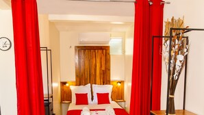 A bedroom with a wooden headboard, a bed with red bedding, a grey bench, and a wooden shelf unit. - Escape in the heart of the city Studio Jacuzzis Sauna and swimming pool (Port-Louis)