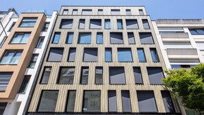 Un edificio a più piani con un design architettonico moderno, caratterizzato da un mix di finestre rettangolari e quadrate e una facciata strutturata.