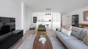Un soggiorno moderno con una televisione a schermo piatto, un tavolino in legno e un divano grigio.