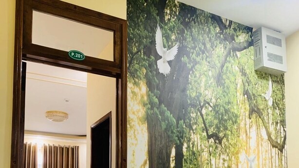 A hotel room with a bed, a desk, and a view of a forest mural. - Green Park 2 Hotel (Quy Nhon Nam)