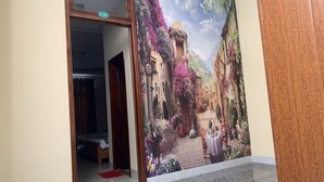 A hallway with a mural of a street scene, a wooden door, and a carpeted floor. - Green Park 2 Hotel (Quy Nhon Nam)