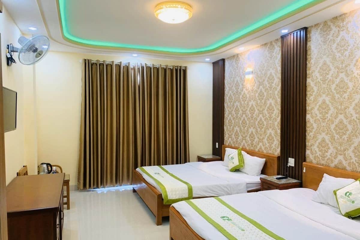 A hotel room with two beds, a desk, a chair, and a large window with curtains.