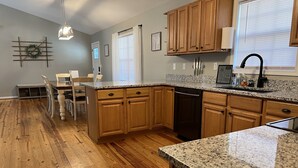 A modern kitchen with wooden cabinets, granite countertops, and a dishwasher. - Adventure Awaits at Acorn Lane (Pisgah Forest)