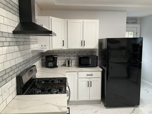 A kitchen with white cabinets, a black stove, a black refrigerator, a microwave, and a toaster.