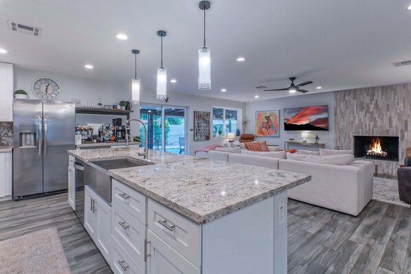 A modern kitchen with a central island, a dining area with a sofa, and a fireplace.