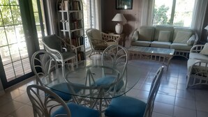 Un área de comedor con una mesa y sillas de vidrio, un sofá y una estantería.
